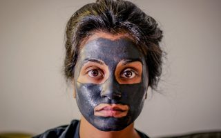 Woman with charcoal face mask on to improve her skin