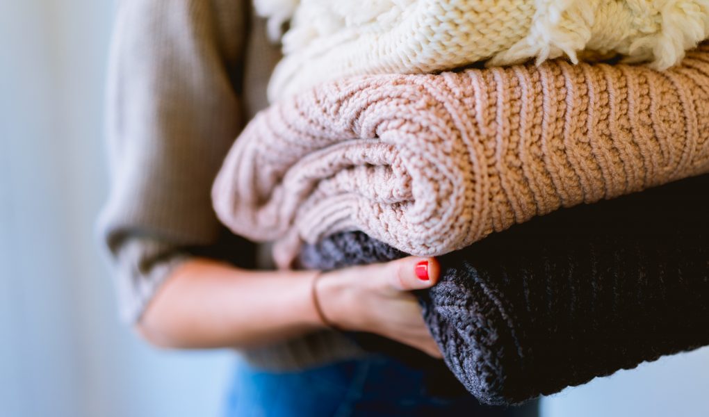 Woman spring cleaning and carrying old jumpers to donate to charity