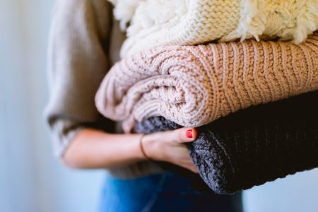 Woman spring cleaning and carrying old jumpers to donate to charity