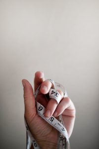 Hand with measuring tape wrapped around it to be used for non-surgical facelift Glasgow