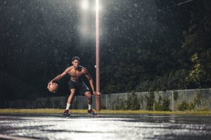 Man playing basketball in the rain for exercise