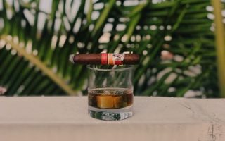 Rare Whisky in a glass on a ledge with a cigar laid across the top.